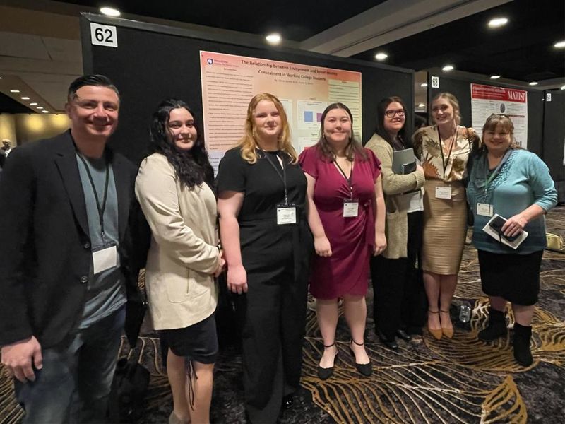 Students and faculty advisors posing in front of research at the Eastern Psychological Association conference.